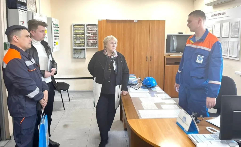 Инспекция охраны труда в офисе - специалист объясняет требования безопасности группе сотрудников в спецодежде